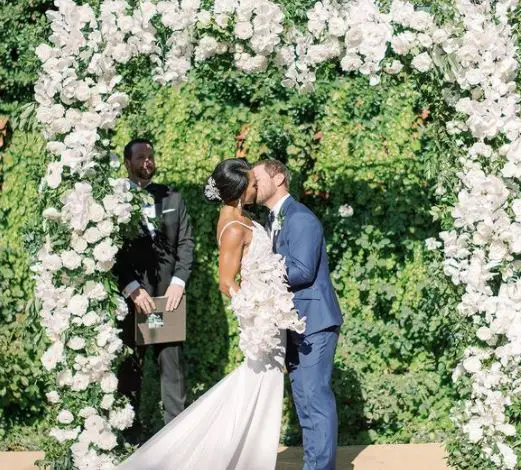 Rhonda Walker and Jason Drumheller sharing a wedding kiss, in front of a luscious green vineyard as their wedding backdrop