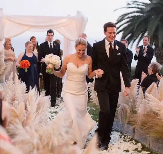 Tory Shulman and her Irish Catholic husband, Brooks Palmer, walk down the aisle holding hands, after taking their vows.